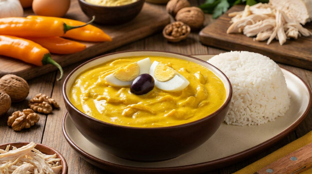 Un plato hondo de ají de gallina con su crema amarilla brillante, decorado con huevo duro y aceituna, servido con arroz blanco graneado