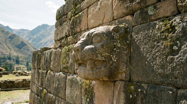 Una Cabeza Clava original de piedra con rasgos felinos incrustada en el muro exterior del Templo Nuevo de Chavín de Huántar bajo la luz del sol